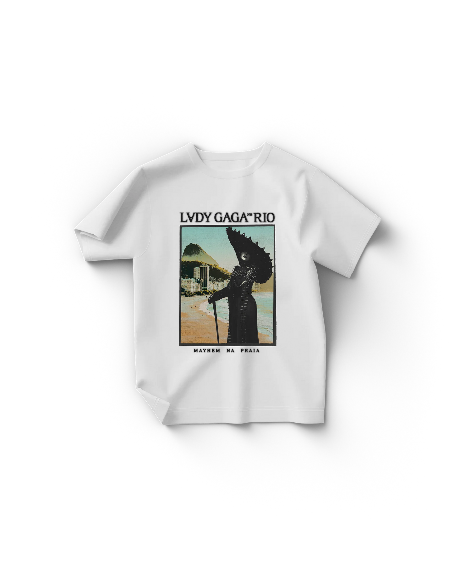 White Lady Gaga t-shirt with a vintage-style poster print showing Gaga in a black spiked outfit and hat, standing on Copacabana Beach with Sugarloaf Mountain in the background. Text reads “LADY GAGA™ RIO” and “MAYHEM NA PRAIA.”