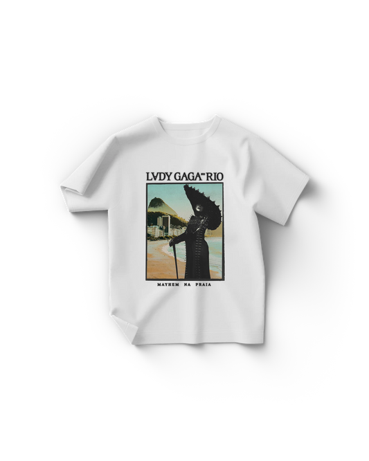 White Lady Gaga t-shirt with a vintage-style poster print showing Gaga in a black spiked outfit and hat, standing on Copacabana Beach with Sugarloaf Mountain in the background. Text reads “LADY GAGA™ RIO” and “MAYHEM NA PRAIA.”