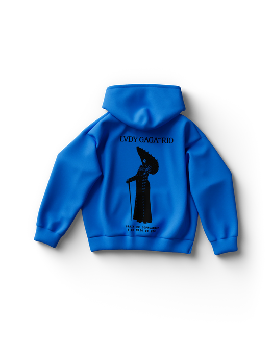Back of bright blue Lady Gaga hoodie featuring a black silhouette of Gaga holding a cane beneath the text “LADY GAGA™ RIO.” Below, it reads “PRAIA DE COPACABANA – 3 DE MARÇO DE 2025,” referencing the beach concert date.

