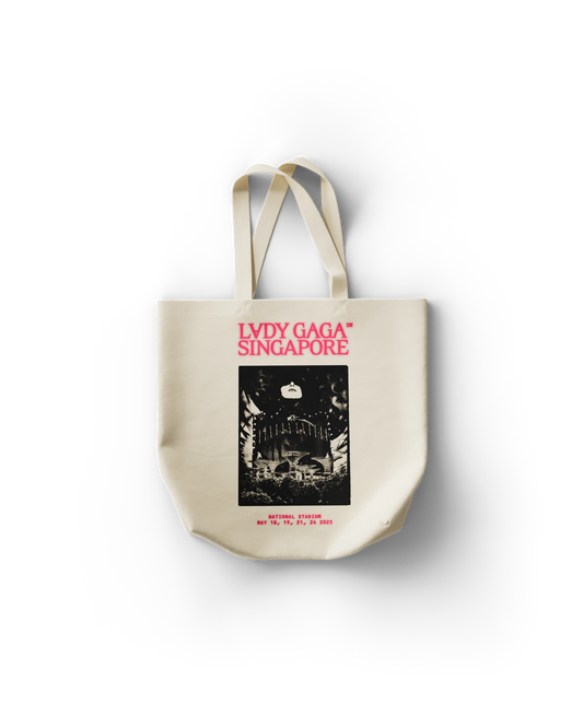 Canvas Lady Gaga tote bag with hot pink text reading “LADY GAGA™ SINGAPORE” above a black-and-white print of Singapore’s National Stadium and Gaga’s face. Bottom text lists concert dates: May 18, 19, 21, and 24, 2025. The bold design celebrates Gaga’s Singapore shows in futuristic tour style.

